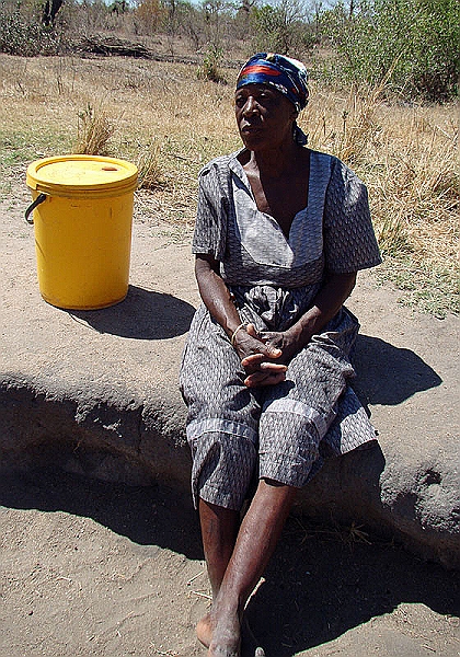 lhvillage1.jpg - A woman waits by the village well to fill up her 5 gallen bucket which she will put on her head and walk a mile back home.